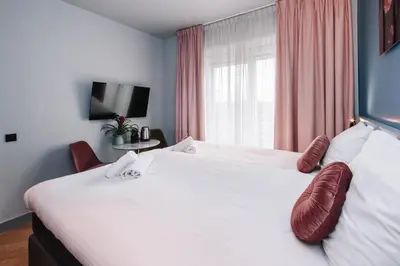 a bedroom with a large white bed with red pillows at Hotel Keur in Zandvoort