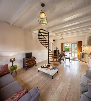 a living room with a spiral staircase and a table at Londons Cottage in Hilversum