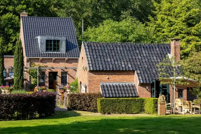 a brick house with a black roof on a yard at Londons Cottage in Hilversum