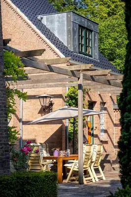 a wooden table with chairs and an umbrella at Londons Cottage in Hilversum