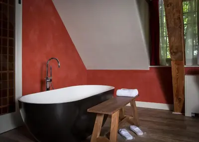 a bathroom with a black tub and a wooden stool at Van Rossum Stadshotel Woerden in Woerden