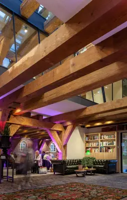a large room with wooden ceilings and people in a library at Van Rossum Stadshotel Woerden in Woerden