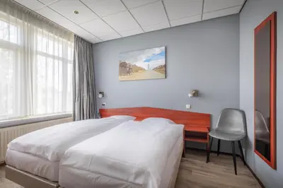 a bedroom with a bed and a desk and a chair at Two Brothers Hotel Astoria in Noordwijk aan Zee