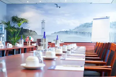 a long table in a restaurant with a lighthouse mural at Two Brothers Hotel Astoria in Noordwijk aan Zee