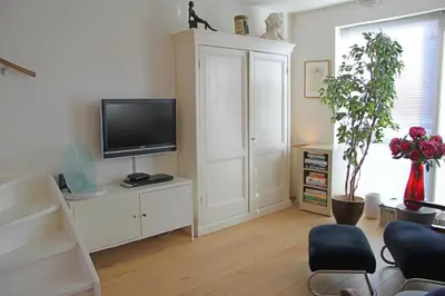 a living room with a tv on a white cabinet at Seapearl in Zandvoort
