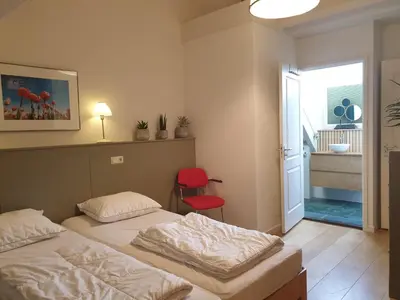 a bedroom with two beds and a red chair at Seapearl in Zandvoort