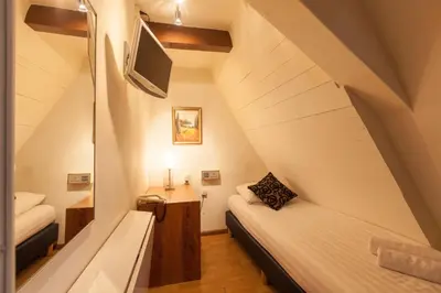 a small room with two beds and a tv at The Townhouse Hotel in Amsterdam