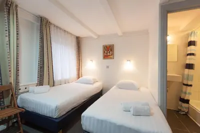 a hotel room with two beds and a chair at The Townhouse Hotel in Amsterdam