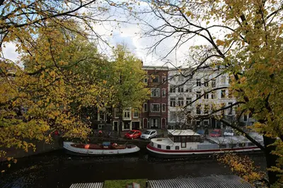 three boats are docked on a river in a city at The Townhouse Hotel in Amsterdam