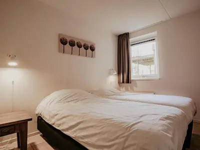 a bedroom with a large white bed with a window at Westergeest in Uitgeest