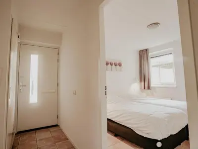 a bedroom with a large white bed and a mirror at Westergeest in Uitgeest