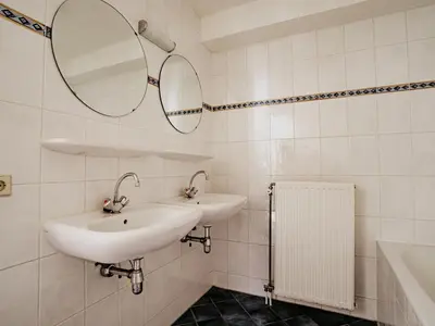a white bathroom with two sinks and a mirror at Westergeest in Uitgeest