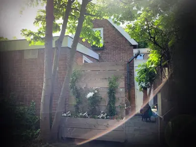 a fence in front of a house with trees at Zomerhuisje Wijk aan Zee in Wijk aan Zee