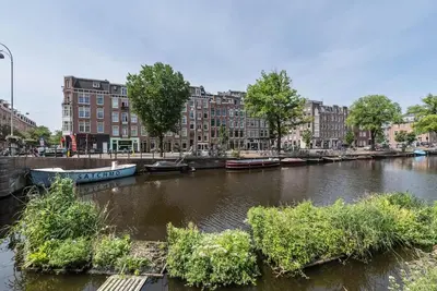 a river with boats in a city with buildings at CanalView Luxury Apartment in Amsterdam