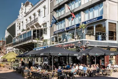a group of people sitting at tables in front of a building at CanalView Luxury Apartment in Amsterdam