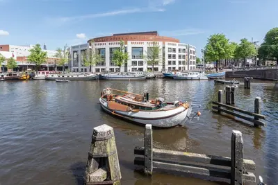 a boat docked at a dock in a river with buildings at CanalView Luxury Apartment in Amsterdam