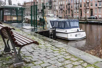 a bench sitting next to a boat in the water at CanalView Luxury Apartment in Amsterdam