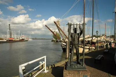 a dock with a statue next to the water with boats at Apartments Waterland in Monnickendam