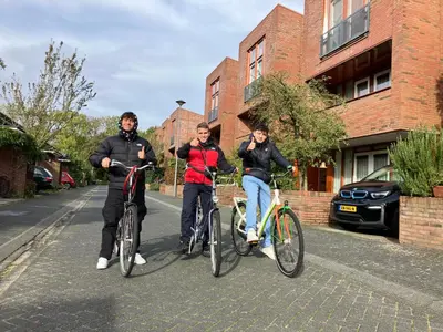 three people riding their bikes on a street at Charming Rooms with free parking in Amsterdam