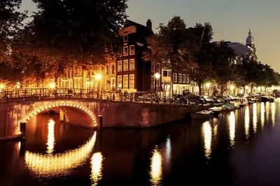 a bridge over a river at night with lights at B&B Blossom in Amsterdam