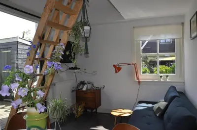 a living room with a blue couch and a ladder at Tiny house Watergang in Watergang