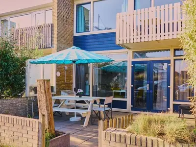 a table with an umbrella in front of a building at Holiday apartment Seapaerdje in Bergen aan Zee
