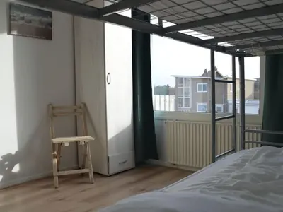 a room with a chair and a bed and a window at Holiday apartment Seapaerdje in Bergen aan Zee