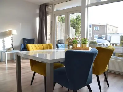 a dining room with a table and yellow chairs at Holiday apartment Seapaerdje in Bergen aan Zee