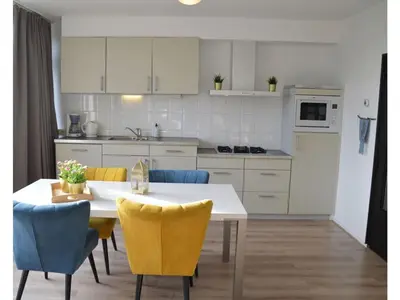 a kitchen with a table and chairs and a kitchen with white cabinets at Holiday apartment Seapaerdje in Bergen aan Zee