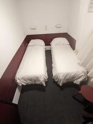 two beds in a room with white sheets at Budget Hotel Ben in Amsterdam