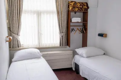 a room with two beds and a window with curtains at Budget Hotel Ben in Amsterdam