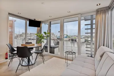 a living room with a couch and a table with chairs at Luxurious waterloft near beach and centre by Weltevreden Experience in Zeewolde