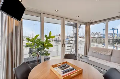 a living room with a table and a large window at Luxurious waterloft near beach and centre by Weltevreden Experience in Zeewolde