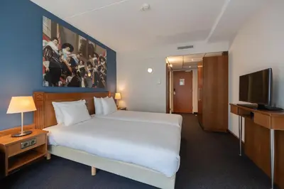 a bedroom with a large white bed and a television at Amrâth Grand Hotel Frans Hals in Haarlem