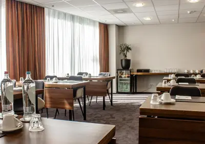 a conference room with tables and chairs and a large window at Amrâth Grand Hotel Frans Hals in Haarlem