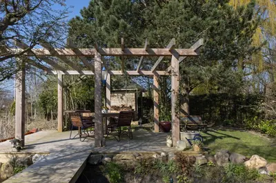 a wooden pergola with a table and chairs in a yard at Vegan B&B De Groene Mus in Wervershoof