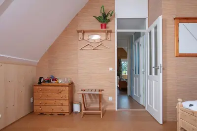 a bedroom with a staircase and a wooden dresser at Vegan B&B De Groene Mus in Wervershoof