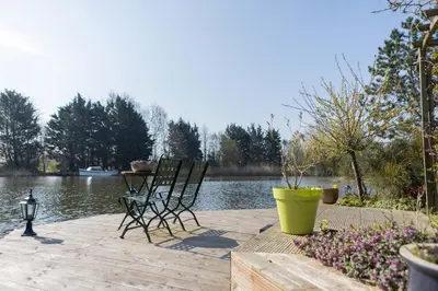two chairs and a table on a dock near the water at Vegan B&B De Groene Mus in Wervershoof
