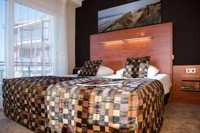 a bedroom with a large bed and a large window at Strandhotel de Vassy in Egmond aan Zee