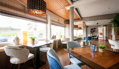 a restaurant with tables and chairs and a large window at Strandhotel de Vassy in Egmond aan Zee