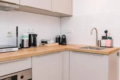 a kitchen with white cabinets and a sink at Simply studio's in Zandvoort