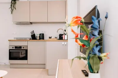 a kitchen with white cabinets and a vase with flowers at Simply studio's in Zandvoort