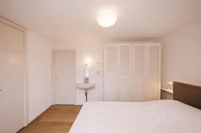 a white bedroom with a bed and a sink at Villa Zuidwest 6, Garden, Dunes & Free parking in Zandvoort