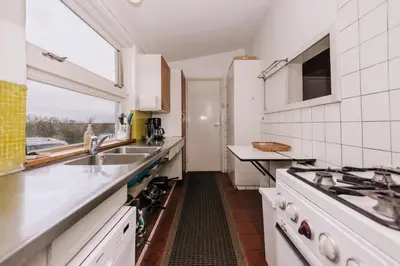 a kitchen with white cabinets and a sink and a window at Villa Zuidwest 6, Garden, Dunes & Free parking in Zandvoort