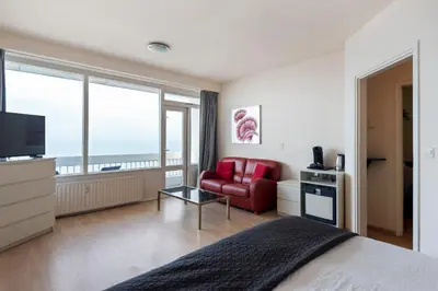 a bedroom with a red chair and a large window at Seaside in Zandvoort