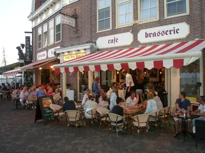 a group of people sitting at tables outside a restaurant at Hotel Cafe Restaurant Van Den Hogen in Volendam