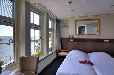 a bedroom with a bed and a mirror and windows at Hotel Cafe Restaurant Van Den Hogen in Volendam