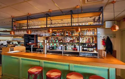 a bar with red stools and bottles of alcohol at Hotel Cafe Restaurant Van Den Hogen in Volendam