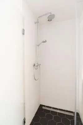 a bathroom with a shower with a black tile floor at The Prinsen in Amsterdam