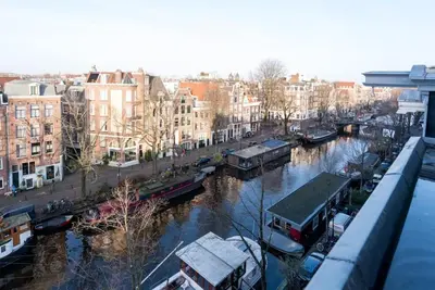 a view of a river with boats and buildings at The Prinsen in Amsterdam